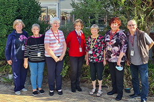 Seven people standing in a garden setting