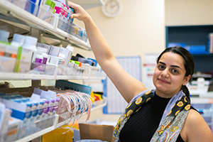 A female pharmacist stands in front of shelves of medications
