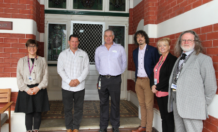 Two women and four men standing outside a building entry