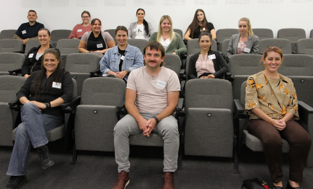 Two men and eleven women sitting in a lecture theatre