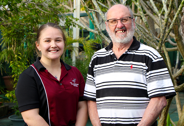 Female occupational therapist standing next to male patient Joseph Kelly-Seymour, smiling to camera.