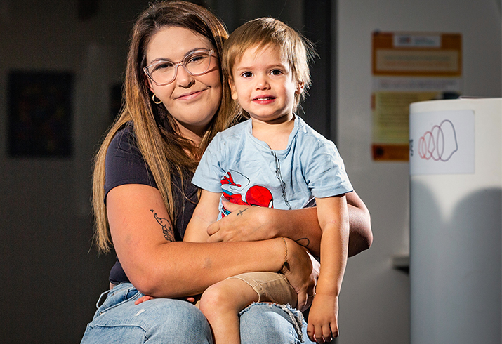 A young Aboriginal boy sits on his mother's knee